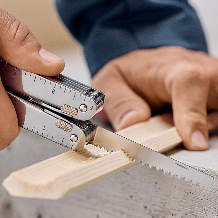 Person using a folding knife with a ruler attachment on a wooden block.