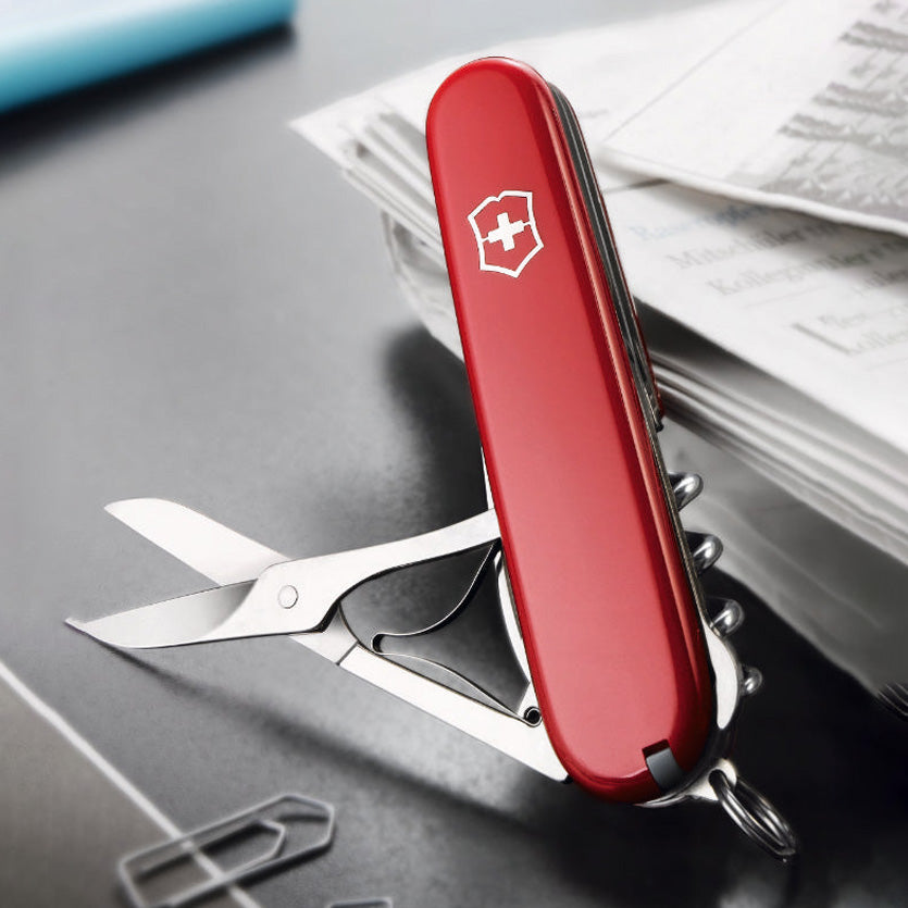 Red Swiss Army knife with multiple tools on a gray surface