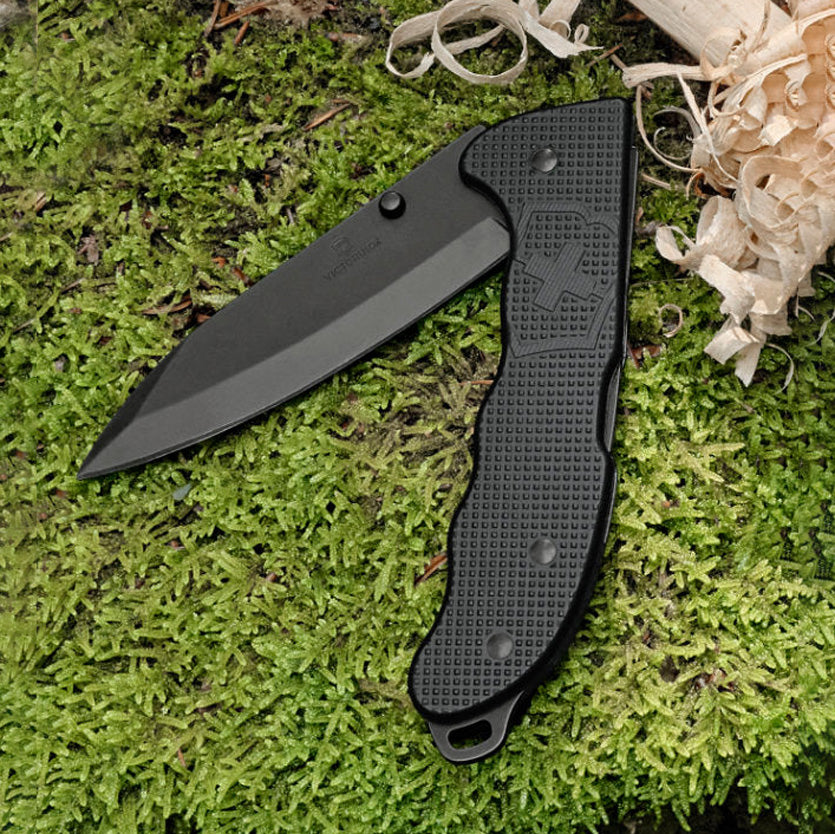 Black folding knife on green moss